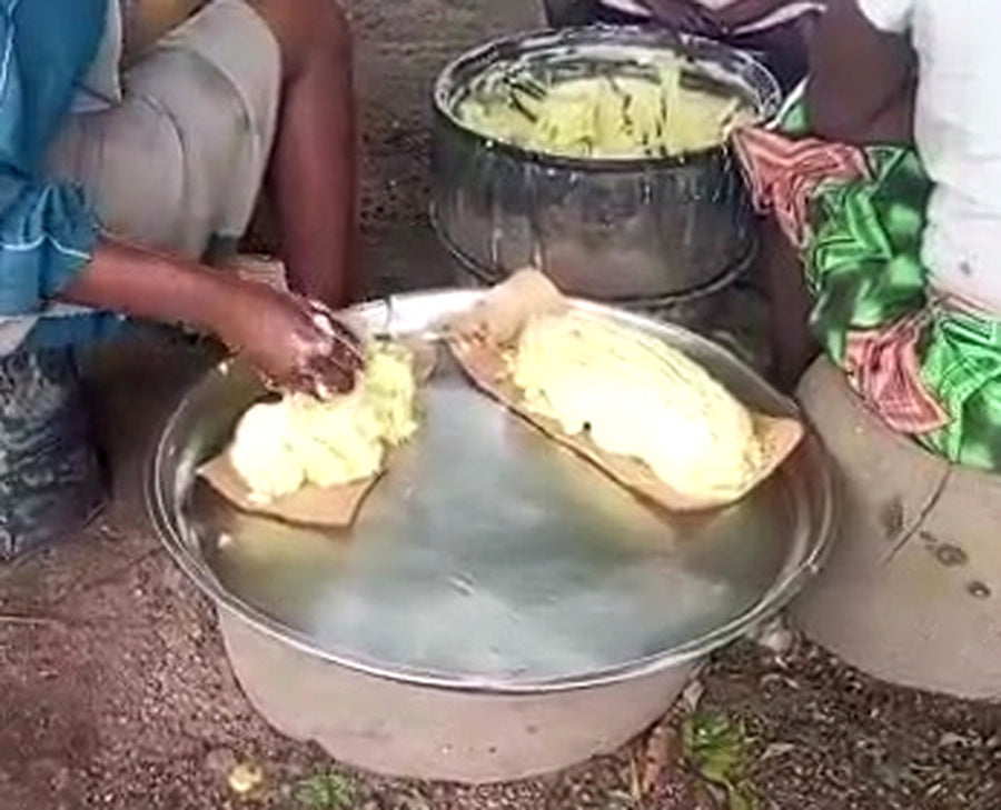 Documentary still showing hands preparing shea butter in metal bowls at the source.